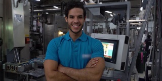 年轻英俊的男子工作在一个胶印机厂面对镜头微笑