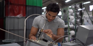 一名男性工程师在一家胶带厂校准机器