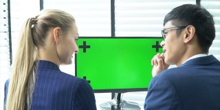 两个商务人士正在用绿色屏幕的笔记本电脑交谈