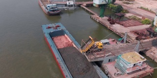 在小港口的驳船上装载建筑材料。