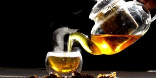 慢镜头，热腾腾的菊花茶从一个玻璃罐里倒进一杯热气腾腾的白烟。