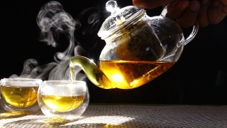 慢镜头，热腾腾的菊花茶从一个玻璃罐里倒进一杯热气腾腾的白烟。视频素材模板下载