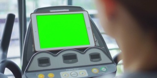 高清慢动作:女人在健身房锻炼，看着电子平板电脑，绿色屏幕