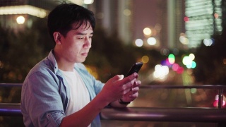 年轻的亚洲男人在晚上用手机视频素材模板下载