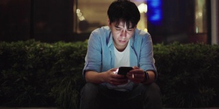 年轻的亚洲男人在晚上用手机