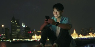 年轻的亚洲男人在晚上用手机