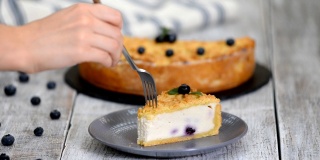 女人吃着美味的奶酪蛋糕和蓝莓。