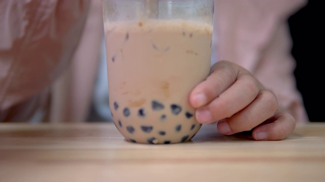 用塑料吸管在桌上搅拌台湾奶茶。