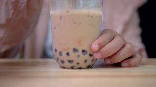 用塑料吸管在桌上搅拌台湾奶茶。视频素材模板下载