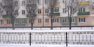 公共汽车行驶的背景是城市里的一座老建筑。下雪，冬天，慢镜头