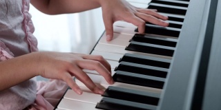 小女孩弹钢琴的慢镜头。手的近景。