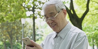 中国老人在公园里使用智能手机