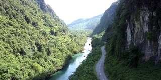 道路和河流在陡峭郁郁葱葱的森林两岸之间蜿蜒曲折