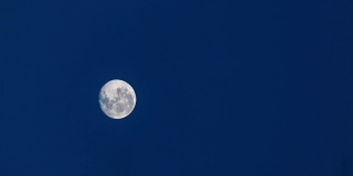 夜晚黎明前深蓝色天空中满月的垂直时间间隔
