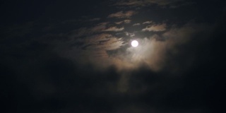 一个实时拍摄的满月在夜空与可见的白云。