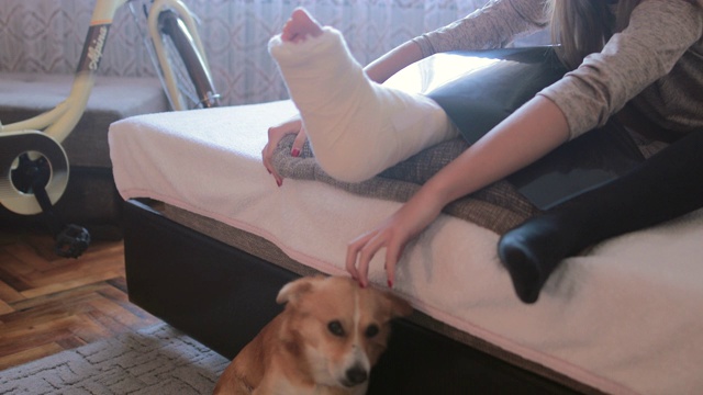 一个断了腿的少女在家里抱着她的狗