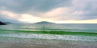 镜头从冲浪板上的女孩移到沙滩上
