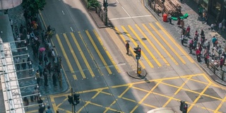 在中国香港尖沙咀地区，人们和出租车穿过一个非常繁忙的十字路口