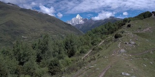 无人机飞向四姑娘山(四姑娘山)，山谷中有一个藏族小村庄(四姑娘山镇)。拍摄于前往海子谷的徒步路线上。