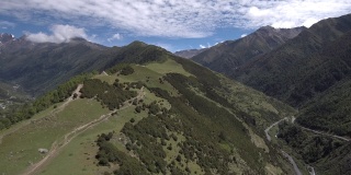 无人机飞向四姑娘山(四姑娘山)，山谷中有一个藏族小村庄(四姑娘山镇)。拍摄于前往海子谷的徒步路线上。