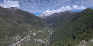 慢慢出现的四姑娘山(四姑娘山)，经幡在风中飘扬，山谷中有一个藏族小村庄(四姑娘山镇)。拍摄于前往海子谷的徒步路线上。