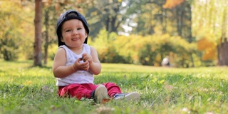快乐的小男孩坐在公园的草地上玩