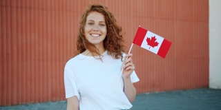 快乐的女学生在户外举着加拿大国旗微笑的慢镜头