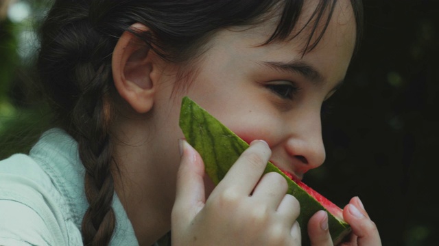 小女孩微笑着吃着西瓜