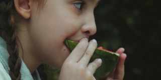 小女孩微笑着在户外吃西瓜