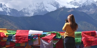 年轻的女摄影师正在梅里雪山拍摄照片