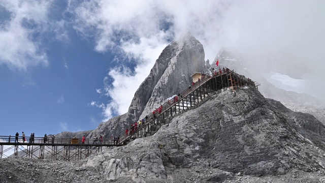 游客爬上玉龙雪山或玉龙雪山的山子斗最高峰的航拍镜头，中国云南丽江