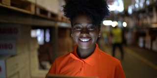 微笑的年轻工人在仓库使用数字平板电脑的肖像