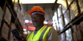 成熟的非洲工人在仓库使用手机