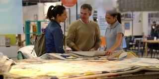 友善的女售货员一边和顾客夫妇愉快地交谈，一边帮他们选择地毯