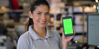 一个商店的女售货员拿着一部智能手机，屏幕上显示着对着摄像头微笑——色度键