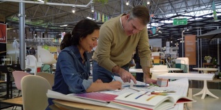 一对拉丁美洲富有创造力的夫妇正在家具店进行家庭装修，他们正在看平板电脑上的色板和草图
