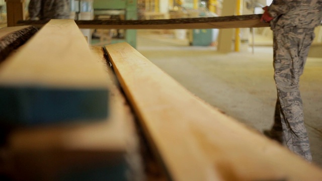 在家具生产车间，工人们将木板放在机器上进行深加工