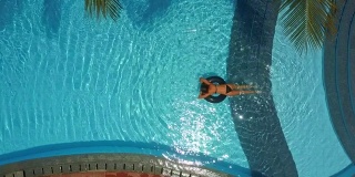 女孩趴在游泳池里转圈游泳