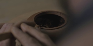 一位工匠用一把木刀将宜兴陶土做成茶壶倒角。茶道用手工陶壶。褐色陶器茶壶。4 k的视频。23.98帧/秒