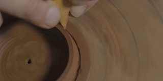 工匠用木刀将宜兴陶土壶盖上多余的陶土取出。茶道用手工陶壶。褐色陶器茶壶。4 k的视频。59.94帧/秒