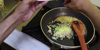 特写厨师准备食物在煎锅和倒蔬菜在锅煮。