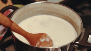准备小麦粉布丁-用牛奶煮细小麦粉，用木勺搅拌视频素材模板下载