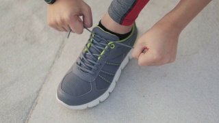在城市公园里系跑鞋的年轻女子。视频素材模板下载