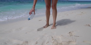 一个年轻的成年女子在海滩上捡一些废弃的塑料瓶