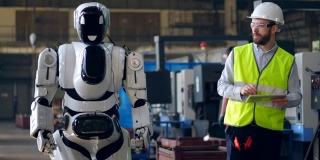 工厂工人用平板电脑检查机器人。
