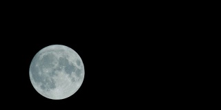 黑暗夜空中的满月。月球从左向右运行。