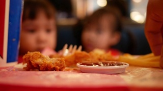 亚洲小女孩和她的妹妹在餐馆吃炸鸡和炸薯条。保健和食品理念。视频素材模板下载