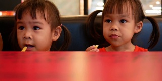 快乐的亚洲小女孩和她的妹妹在餐厅吃薯条。保健和食品理念。