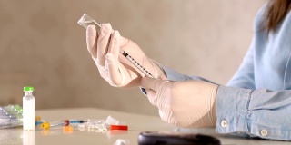 一个戴手套的女孩正在用胰岛素注射器取短效胰岛素。