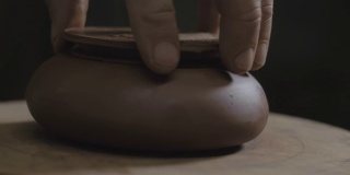 工匠在宜兴陶壶上试盖。为中国茶道制作的手工陶壶。褐色陶器茶壶。4 k的视频。59.94帧/秒